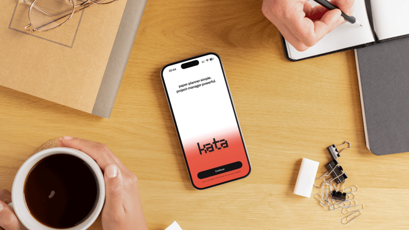 An iPhone on a wooden desk showing kata’s welcome screen: syncs privately with iCloud, no account needed